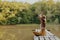 A woman yogi sits with her back to the riverbank on a bridge and meditates on relaxing her body in nature