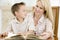 Woman and young boy reading book in dining room