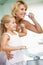 Woman and young girl in bathroom brushing teeth