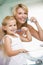 Woman and young girl in bathroom brushing teeth