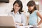 Woman and young girl in kitchen with laptop