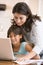 Woman and young girl in kitchen with laptop