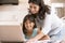 Woman and young girl in kitchen with laptop