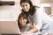 Woman and young girl in kitchen with laptop