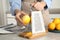 Woman zesting lemon at table indoors, closeup