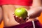 Womanin sportswear holding an apple. People, fitness and healthcare concept