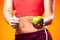 Womanin sportswear holding an apple and showing thumb up gesture. People, fitness and healthcare concept