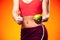 Womanin sportswear holding an apple and showing thumb up gesture. People, fitness and healthcare concept