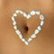 Womans belly with heart made of white pebble stones