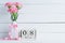 Womans day concept. Pink carnation flower in vase with March 8 text on wooden block calendar on white wooden background