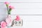 Womans day concept. Pink carnation flower in vase and red heart with March 8 text on wooden block calendar on white wooden