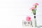 Womans day concept. Pink carnation flower in vase and red heart with March 8 text on wooden block calendar on white wooden