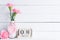 Womans day concept. Pink carnation flower in vase and red heart with March 8 text on wooden block calendar on white wooden