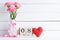 Womans day concept. Pink carnation flower in vase and red heart with March 8 text on wooden block calendar on white wooden