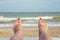 Womans feet on the beach. Female legs and feets with red nails on sunbed on the beach. Summer relaxation on sea background