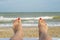 Womans feet on the beach. Female legs and feets with red nails on sunbed on the beach. Summer relaxation on sea background