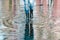 Womans feet with black rubber boots and blue jeans standing in a puddle of water after rain on a city street. Front view