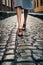 womans feet in stylish shoes walking on cobblestone