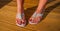 Womans feet in white tri strap summertime sandals on new wooden deck.