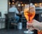 Womans hand holding a full spritz drink at a bar