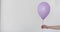 Womans hand holds purple balloon white background