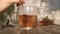 Womans hand stir sugar in sweet tea cup of hot tea in glass cup.