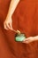 Womans hand uses match to light aromatic candle in recycled glass jar on terracotta color