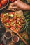 Womans hands adding spices to Turkish Chopard Salad with vegetables