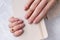 Womans hands with nude beige pink nail design holding notepad