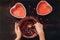 Womans hands removes last drops of dough with spoon from deep bowl for baking red heart-shaped cake