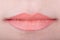 Womans lips with orange glossy lipstick