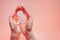 Womans palms pressed together and keep paper embryo. Light coral background with copy space. Hands on the left side. Soft focus