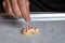 Womanâ€™s hand dropping sugar sprinkles onto a heart shaped frosted sugar cookie