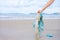 Womanâ€™s hand picking up used plastic bag on sand beach, cleaning seaside beach.  Environmental pollution, Ecological problem and