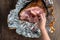 Womanâ€™s hand pulling a piece of ham off a spiral cut glazed and cooked ham in a foil wrapper on a wood table