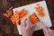 Womanâ€™s hands chopping baby carrots, white cutting board on wood butcher block