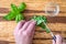 Womanâ€™s hands chopping fresh basil with a paring knife on a rustic grove bamboo cutting board, small glass bowl