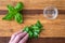 Womanâ€™s hands chopping fresh basil on a rustic grove bamboo cutting board, small glass bowl