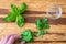 Womanâ€™s hands chopping fresh basil on a rustic grove bamboo cutting board, small glass bowl