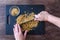 Womanâ€™s hands holding chef knife and chopping walnuts, black cutting board, glass bowl, dark wood table