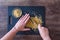 Womanâ€™s hands holding chef knife and chopping walnuts, black cutting board, glass bowl, dark wood table