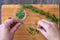 Womanâ€™s hands pulling fresh rosemary leaves off a sprig, sprigs of rosemary with on a bamboo cutting board, chopped rosemary, pa