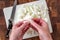 Womanâ€™s hands separating an onion, white cutting board on wood butcher block