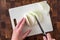 Womanâ€™s hands slicing an onion, white cutting board on wood butcher block