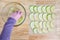 Womanâ€™s hands taking granny smith apple slices out of a glass bowl and laying them out on a mesh tray for dehydrating