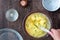 Womanâ€™s hands whisking raw egg mixture with chopped broccoli in glass bowl, on a wood table