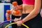 Women with bare belly working dumbbells and hoop at gym.