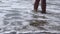 Women with barefoot standing on the sand by the sea, wave crashing into her feet. Self reflection time, being lonely