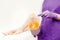 Women beautician holds jar wax of paste for sugar depilation shugaring, white background legs of young girl