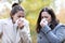 Women blowing on tissue with flu symptoms in a park in winter